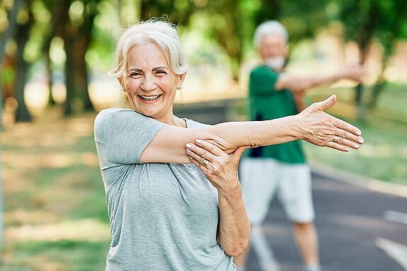 Patientin Gymnastik im Park Frau macht Dehnübungen im Park.